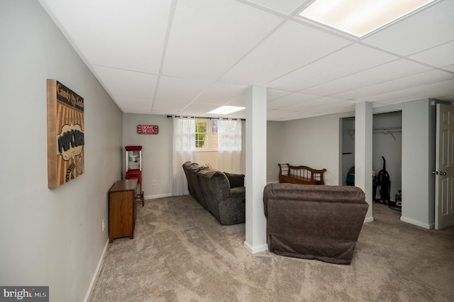 living area featuring carpet floors, baseboards, and a paneled ceiling