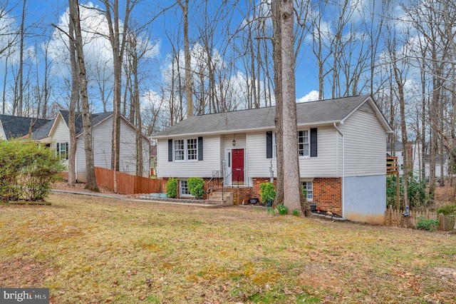 raised ranch featuring a front lawn and fence