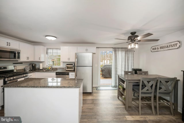 kitchen featuring dark stone countertops, white cabinets, stainless steel appliances, and plenty of natural light