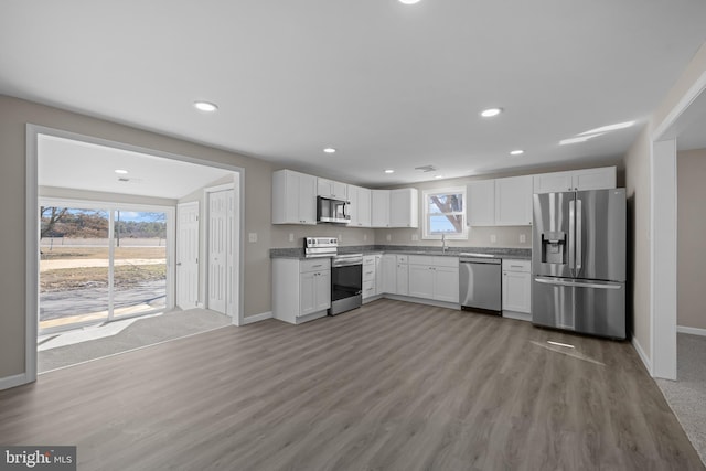 kitchen featuring white cabinets, light wood finished floors, stainless steel appliances, and a sink