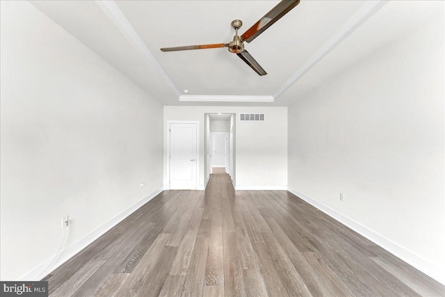 interior space with a tray ceiling, visible vents, ceiling fan, wood finished floors, and baseboards