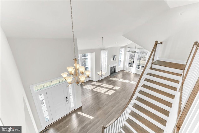 foyer with baseboards, dark wood finished floors, stairway, a fireplace, and a chandelier