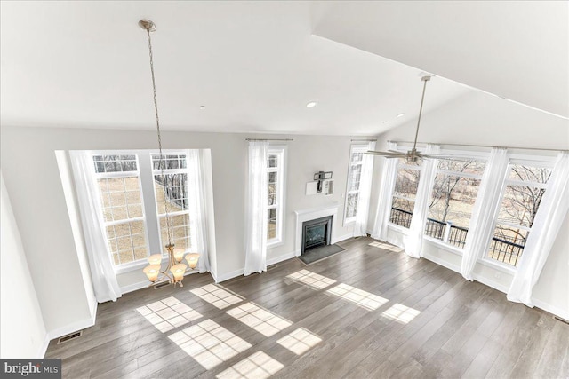 unfurnished living room featuring lofted ceiling, ceiling fan, baseboards, dark wood-style floors, and a glass covered fireplace