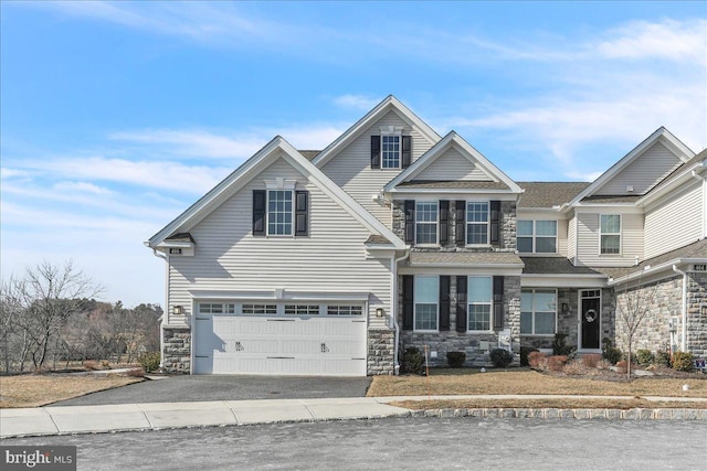 view of front of house with driveway, stone siding, and a garage