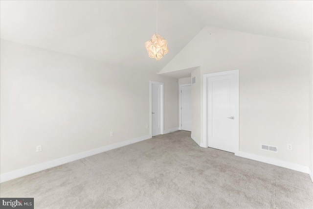 unfurnished bedroom with light carpet, high vaulted ceiling, visible vents, and baseboards