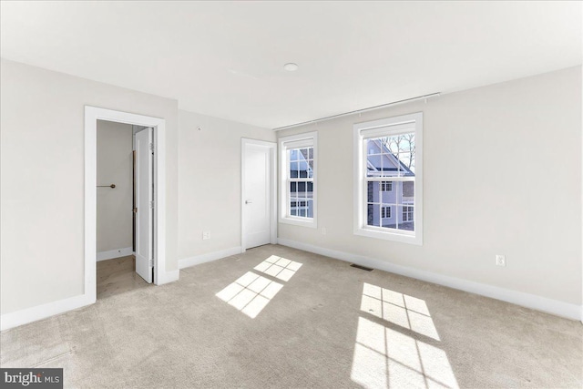 unfurnished bedroom with light carpet, visible vents, and baseboards