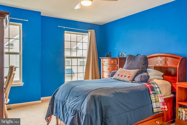 carpeted bedroom with ceiling fan and baseboards