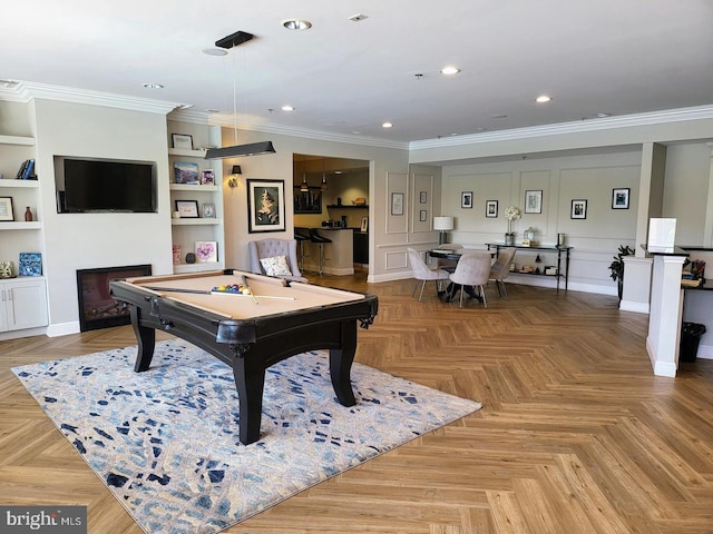 playroom featuring built in features, crown molding, a fireplace, recessed lighting, and a decorative wall