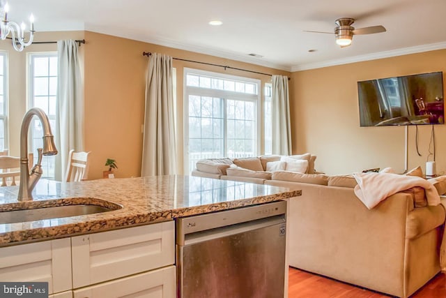 kitchen with a sink, a healthy amount of sunlight, light wood finished floors, and dishwasher