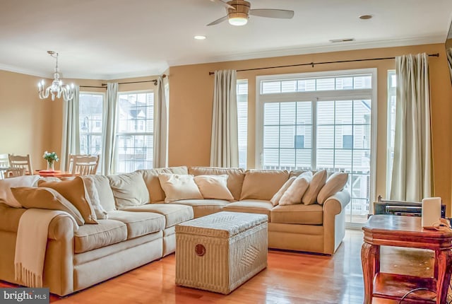 living area with light wood-style floors, recessed lighting, crown molding, and ceiling fan with notable chandelier