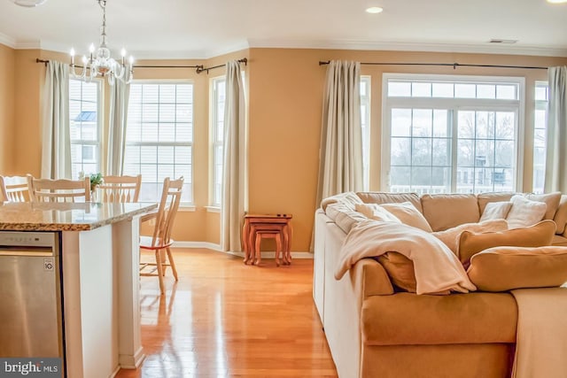 living area featuring ornamental molding, light wood-type flooring, a notable chandelier, and baseboards