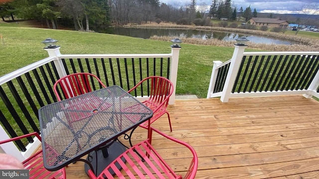 wooden terrace with a yard, outdoor dining space, and a water view