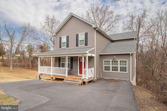 traditional-style house featuring covered porch, roof with shingles, and driveway