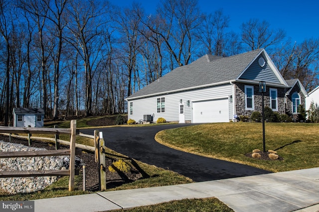 view of side of property with aphalt driveway, an outbuilding, a yard, a shed, and stone siding