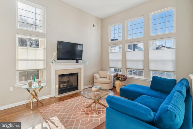 living area with a fireplace, wood finished floors, visible vents, and baseboards