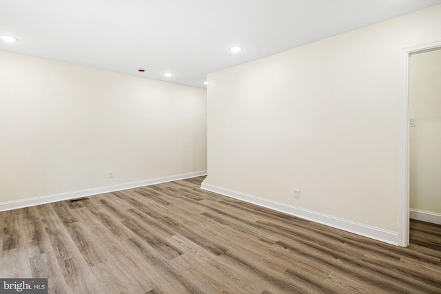 spare room featuring recessed lighting, wood finished floors, and baseboards