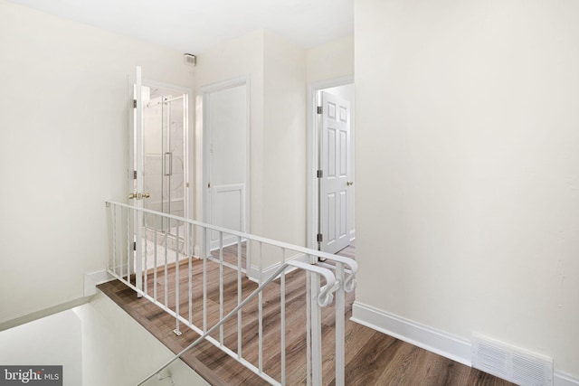 corridor featuring wood finished floors, visible vents, and baseboards