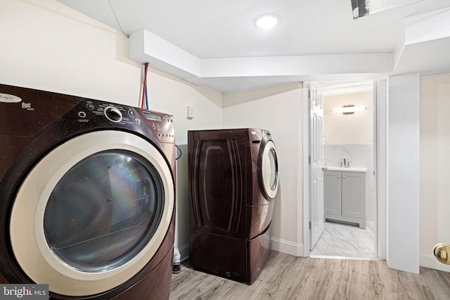 laundry area featuring laundry area, washer and clothes dryer, light wood-type flooring, and a sink