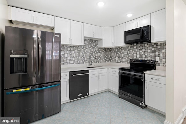 kitchen with light countertops, decorative backsplash, white cabinets, a sink, and black appliances