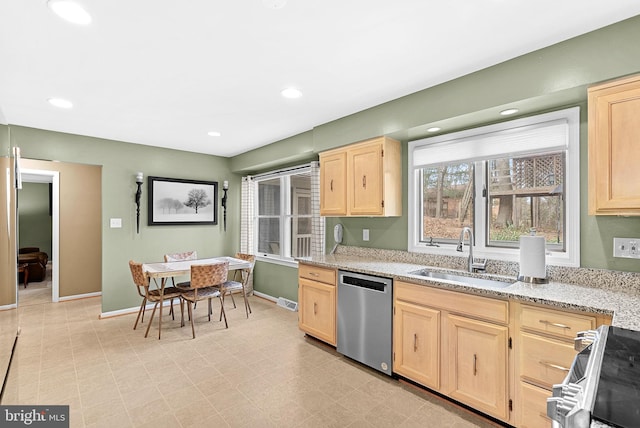 kitchen with stainless steel appliances, light brown cabinets, a sink, and light stone countertops