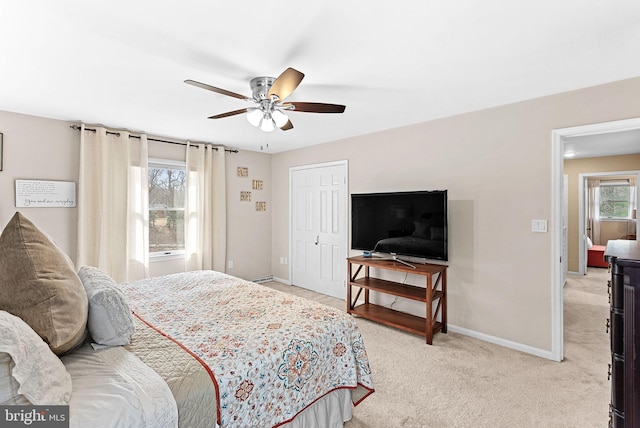 bedroom featuring multiple windows, light colored carpet, and baseboards