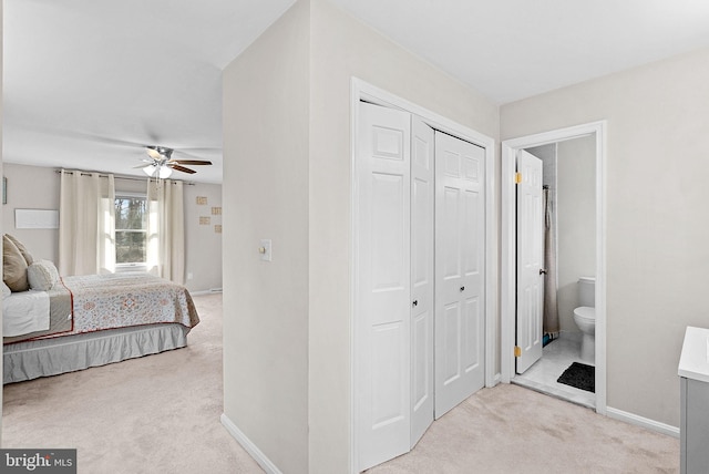 bedroom featuring connected bathroom, baseboards, a closet, and light colored carpet