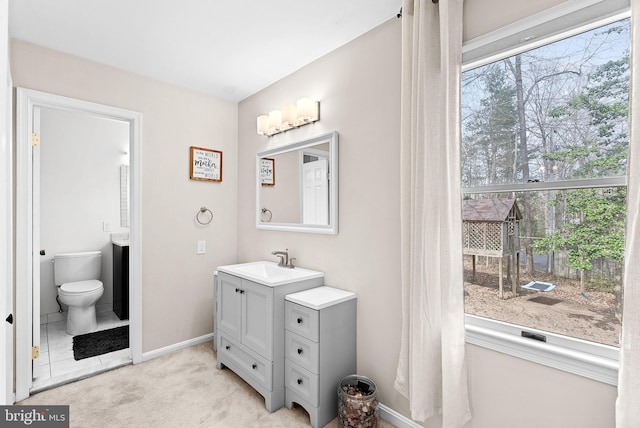 bathroom featuring toilet, baseboards, and vanity