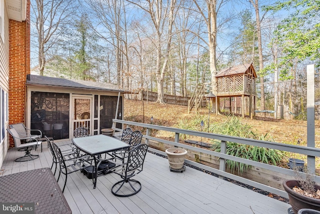 deck with outdoor dining area, fence, and a sunroom