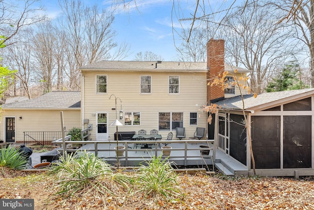 back of house featuring a deck, a sunroom, and a chimney