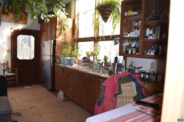 kitchen with freestanding refrigerator, brown cabinets, and a sink