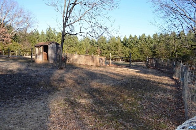 view of yard with a forest view, fence, and an outdoor structure