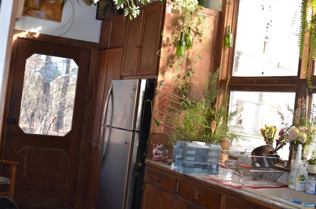 kitchen with brown cabinets, light countertops, and freestanding refrigerator