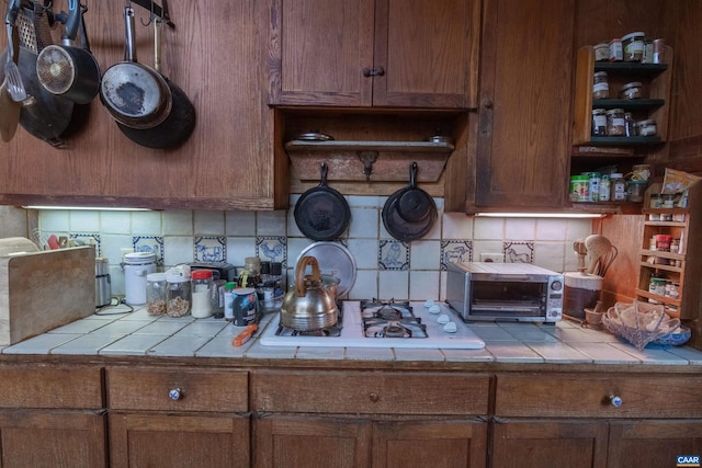 kitchen with backsplash, tile countertops, and open shelves