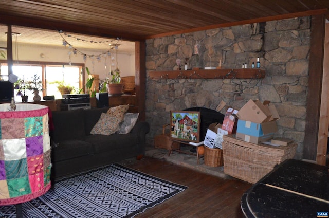 living area featuring wooden ceiling, wood finished floors, and a stone fireplace