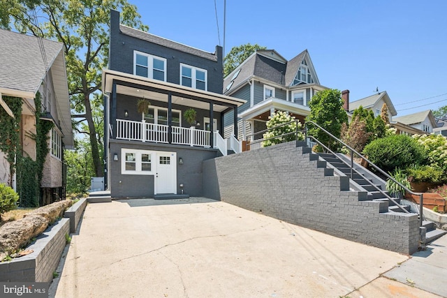 view of front of property with a balcony, stairway, and brick siding