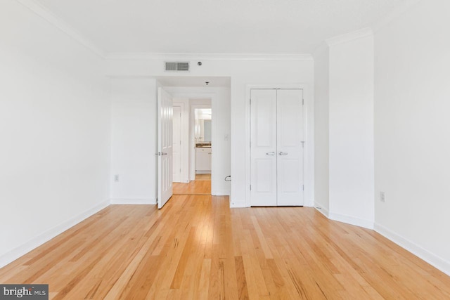 unfurnished bedroom featuring light wood-type flooring, baseboards, visible vents, and crown molding