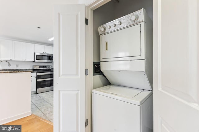 laundry area with light wood-type flooring, stacked washer / dryer, laundry area, and a sink