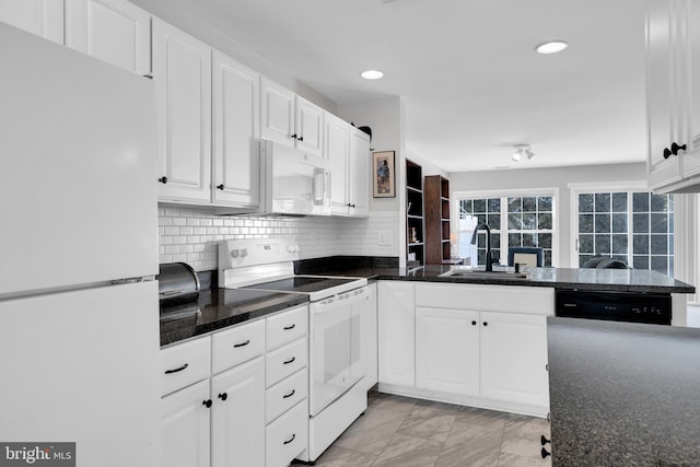 kitchen with tasteful backsplash, white cabinetry, a sink, white appliances, and a peninsula