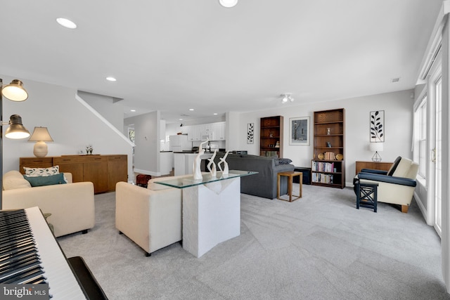 living area featuring baseboards, recessed lighting, and light colored carpet