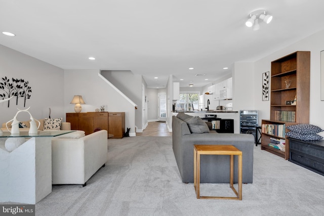 living room with recessed lighting, light carpet, and baseboards