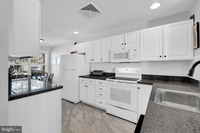 kitchen with white appliances, white cabinetry, visible vents, and a sink