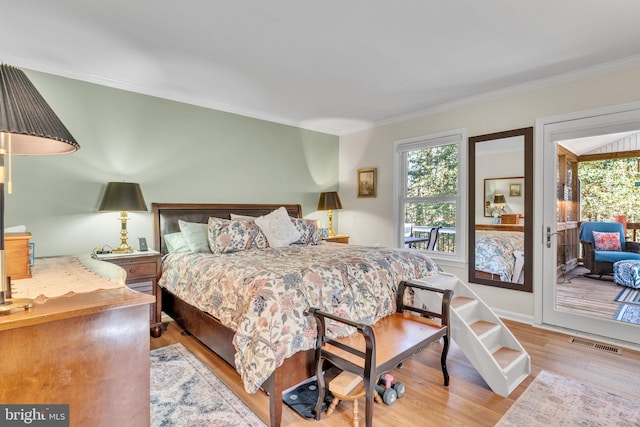 bedroom with ornamental molding, light wood finished floors, multiple windows, and visible vents