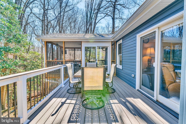 wooden deck featuring outdoor dining area and a sunroom