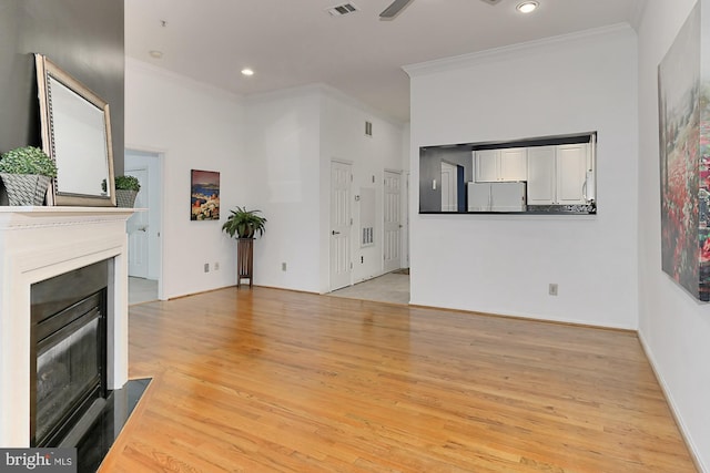 unfurnished living room featuring light wood finished floors, recessed lighting, a fireplace with flush hearth, and crown molding