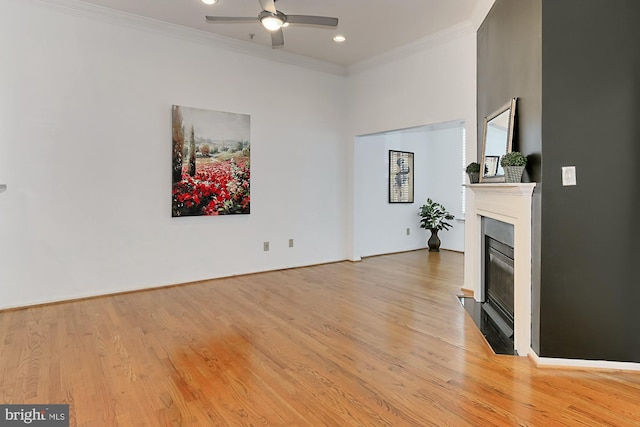 living room with light wood-style flooring, ornamental molding, and a glass covered fireplace