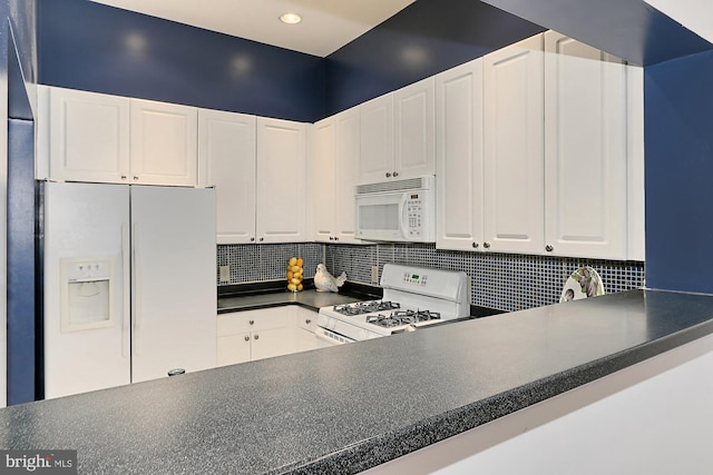 kitchen with white appliances, dark countertops, white cabinetry, and tasteful backsplash