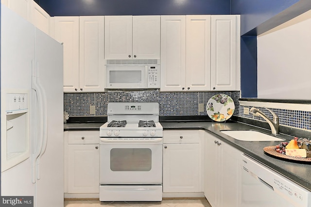 kitchen with dark countertops, white appliances, white cabinetry, and a sink