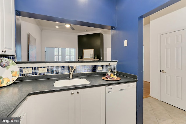 kitchen with light tile patterned floors, white dishwasher, a sink, white cabinetry, and dark countertops