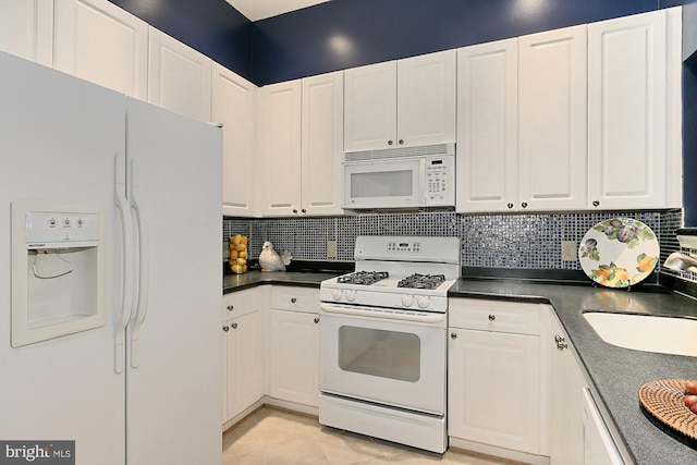 kitchen featuring white appliances, a sink, white cabinetry, backsplash, and dark countertops