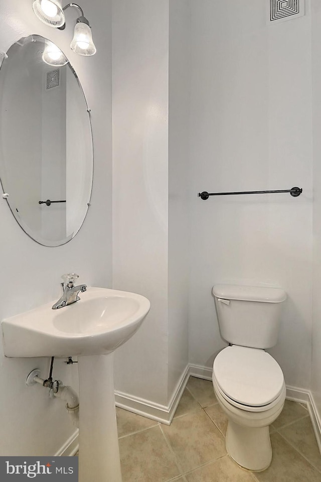 half bath with baseboards, visible vents, toilet, and tile patterned floors